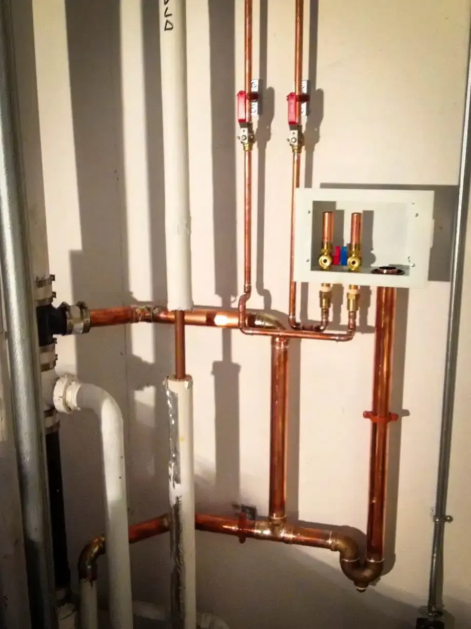 Copper pipes are connected to a white wall in a room.