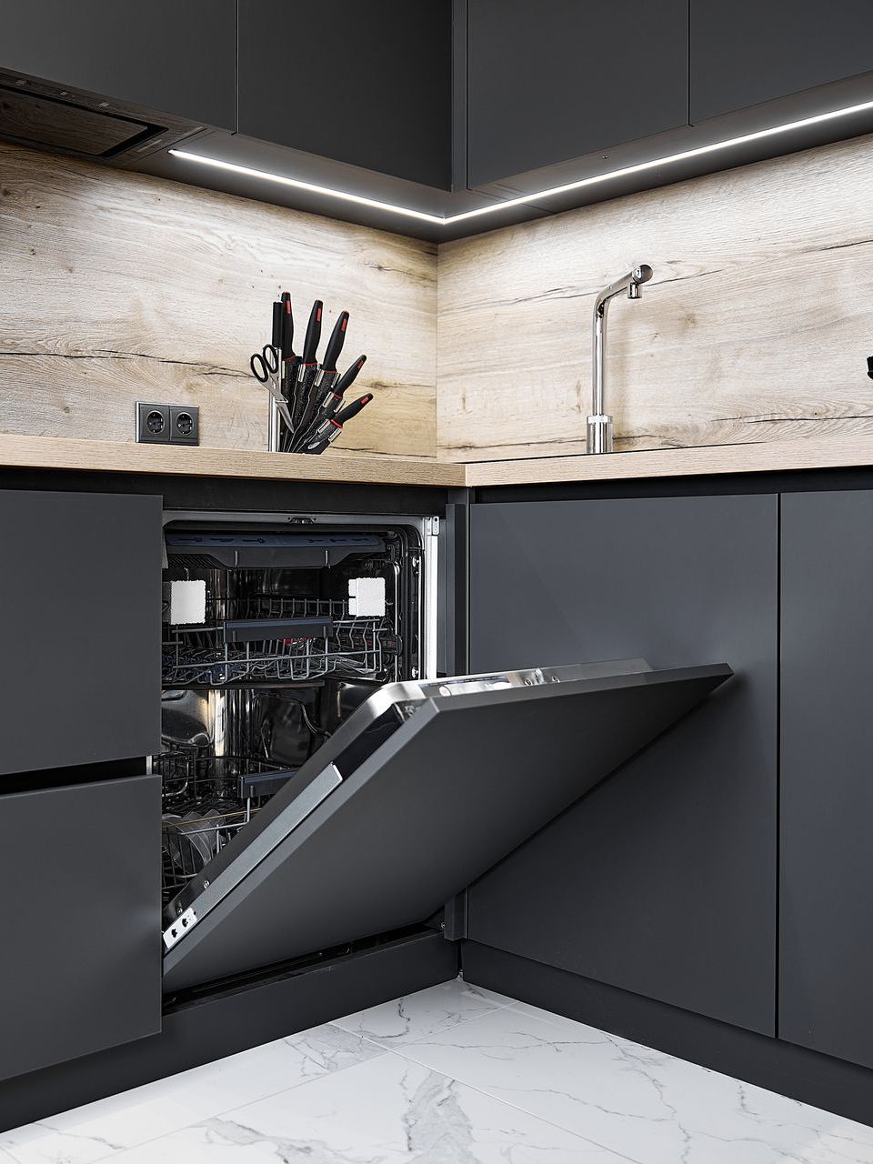 A kitchen with black cabinets and a dishwasher with the door open.