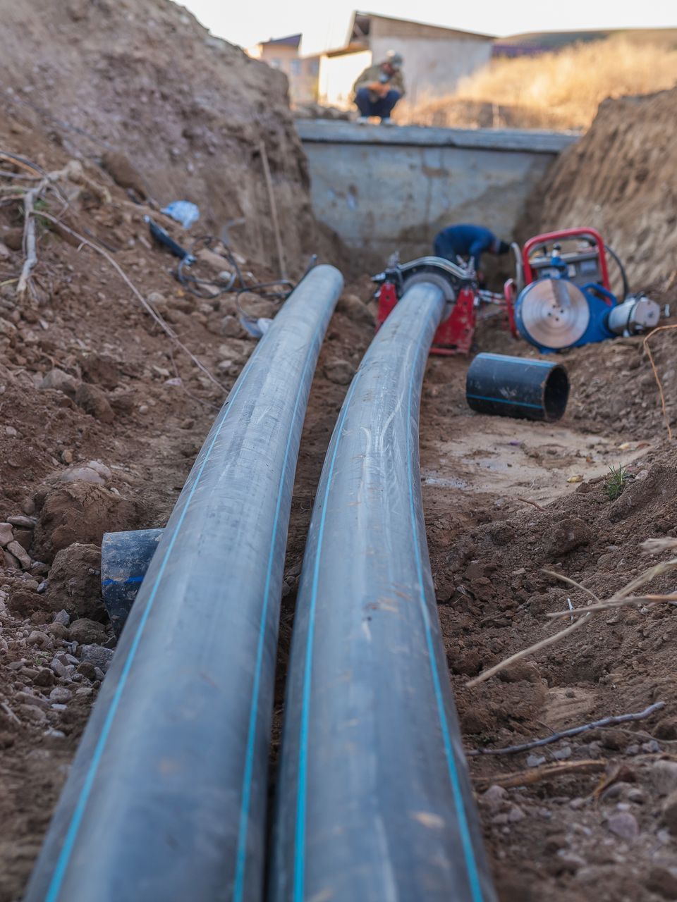 Two water pipes are being installed in a trench.