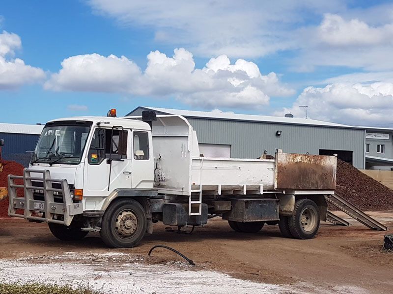 A white dump truck is parked in front of a building.