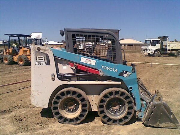 A toyota skid steer is parked in a dirt field