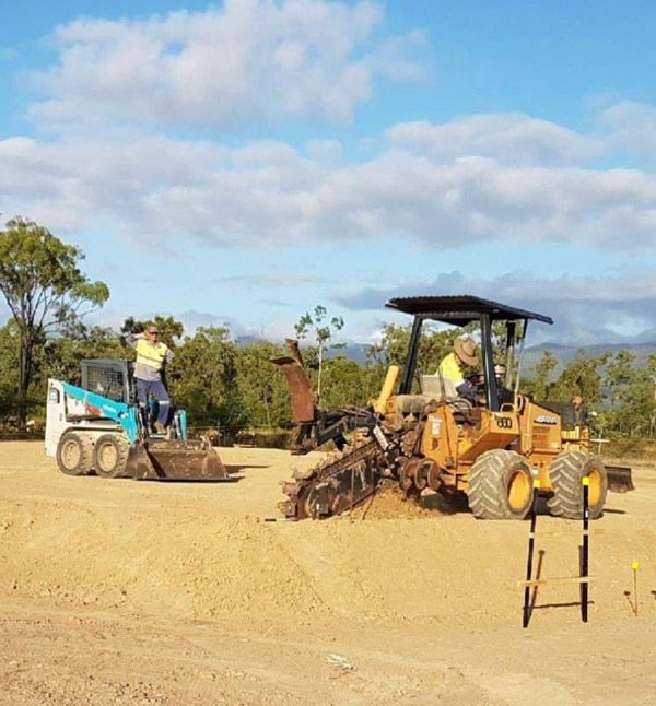 A man is driving a tractor in a dirt field
