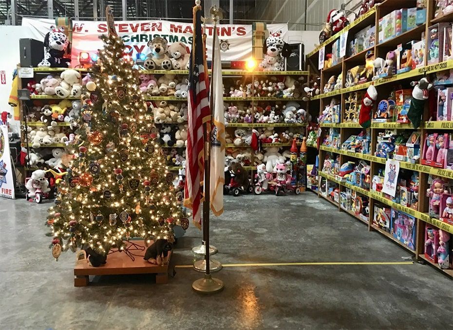 A Christmas tree display in a toy store aisle with shelves of colorful toys on both sides