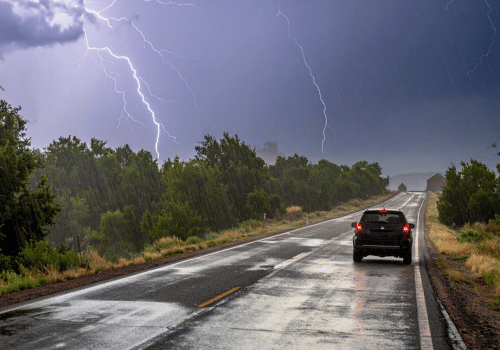 Car driving on a wet road during a thunderstorm with lightning strikes
