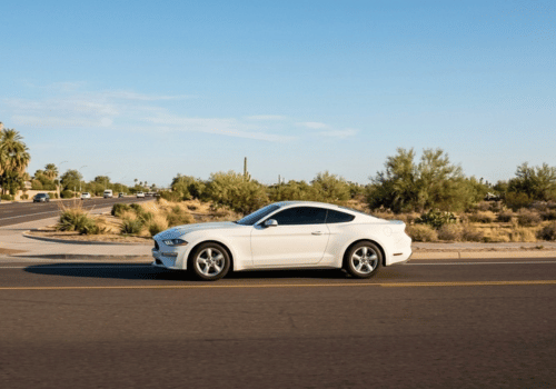 White Ford Mustang driving along a desert road in Arizona