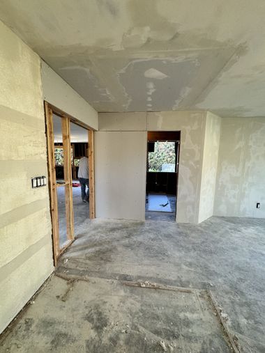 Empty unfinished room with bare walls, exposed wood framing, and a window opening to the outside.