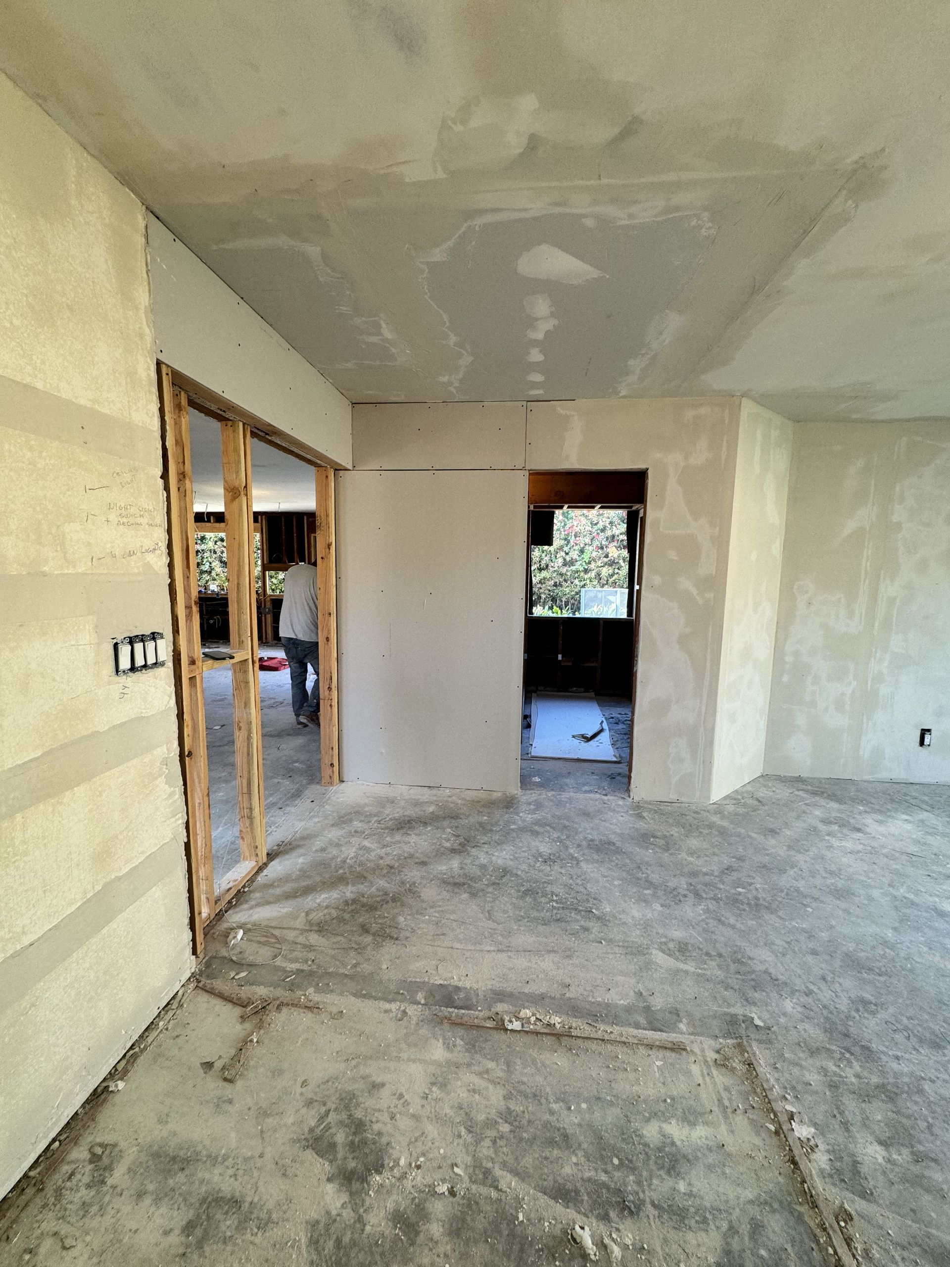 Empty unfinished interior room with bare walls, concrete floor, and open doorway to another room.