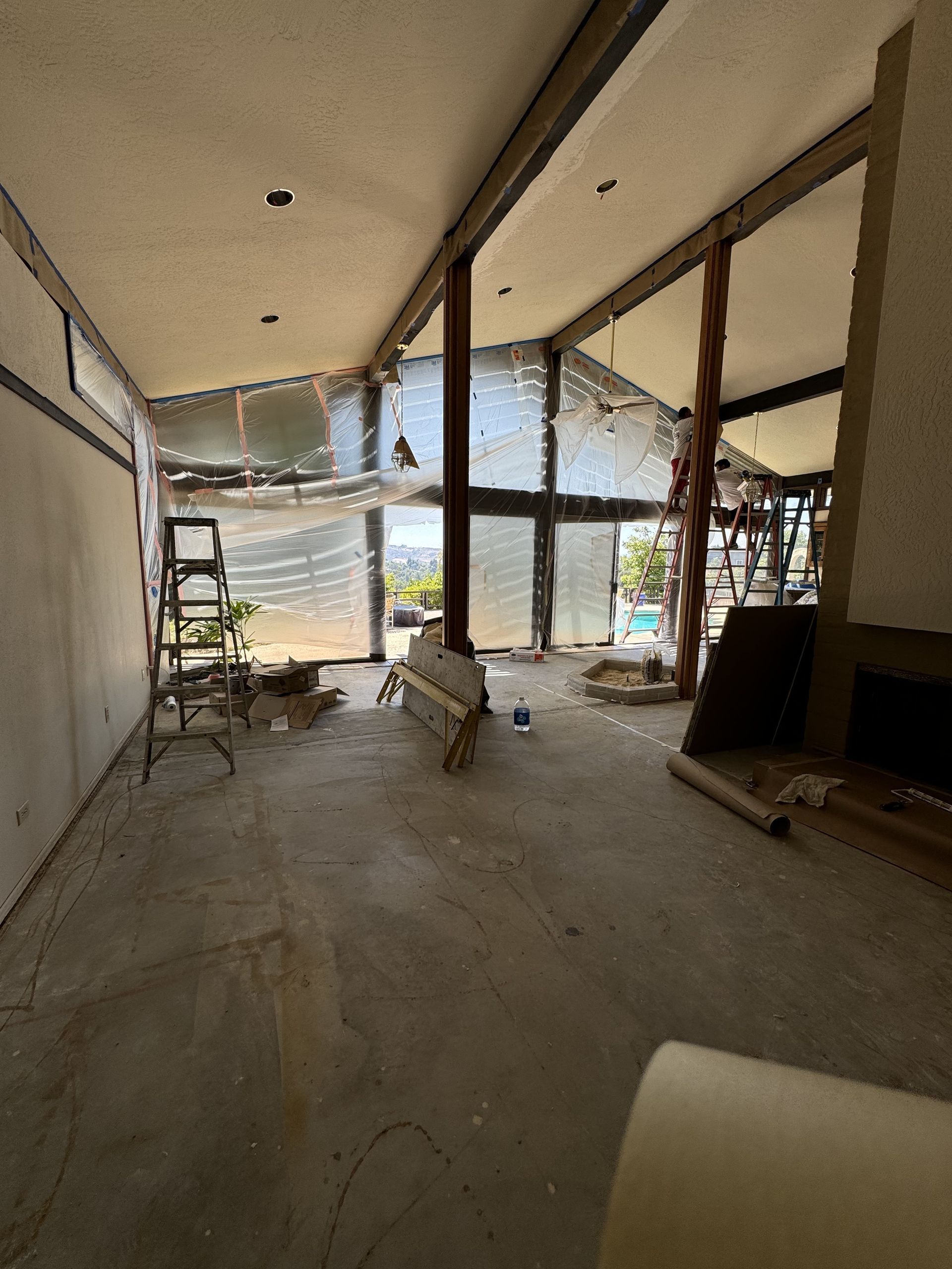 Empty unfinished room with concrete floor, large windows, and construction materials scattered inside.
