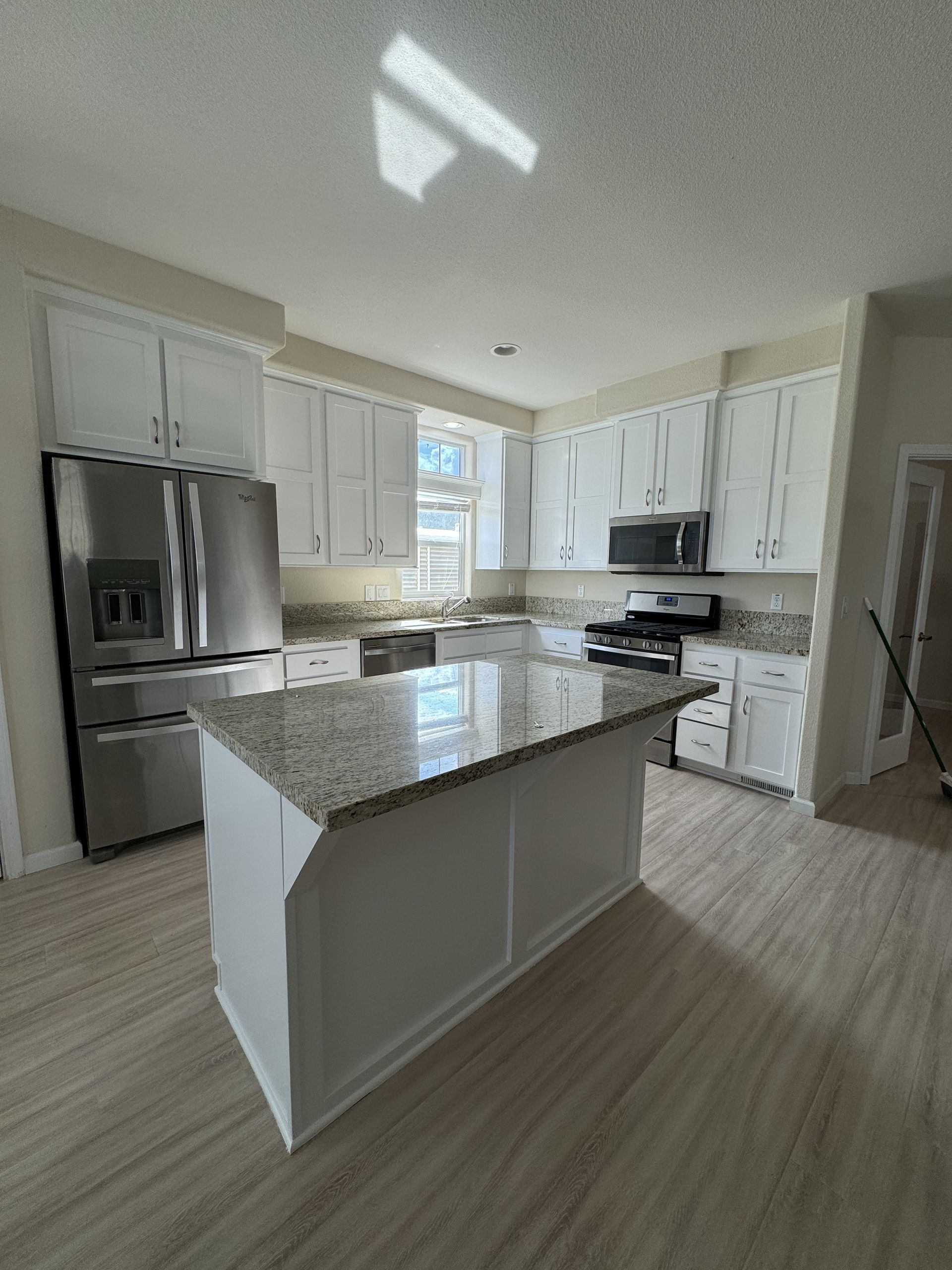 Bright modern kitchen with white cabinets, stainless steel appliances, and a gray island.