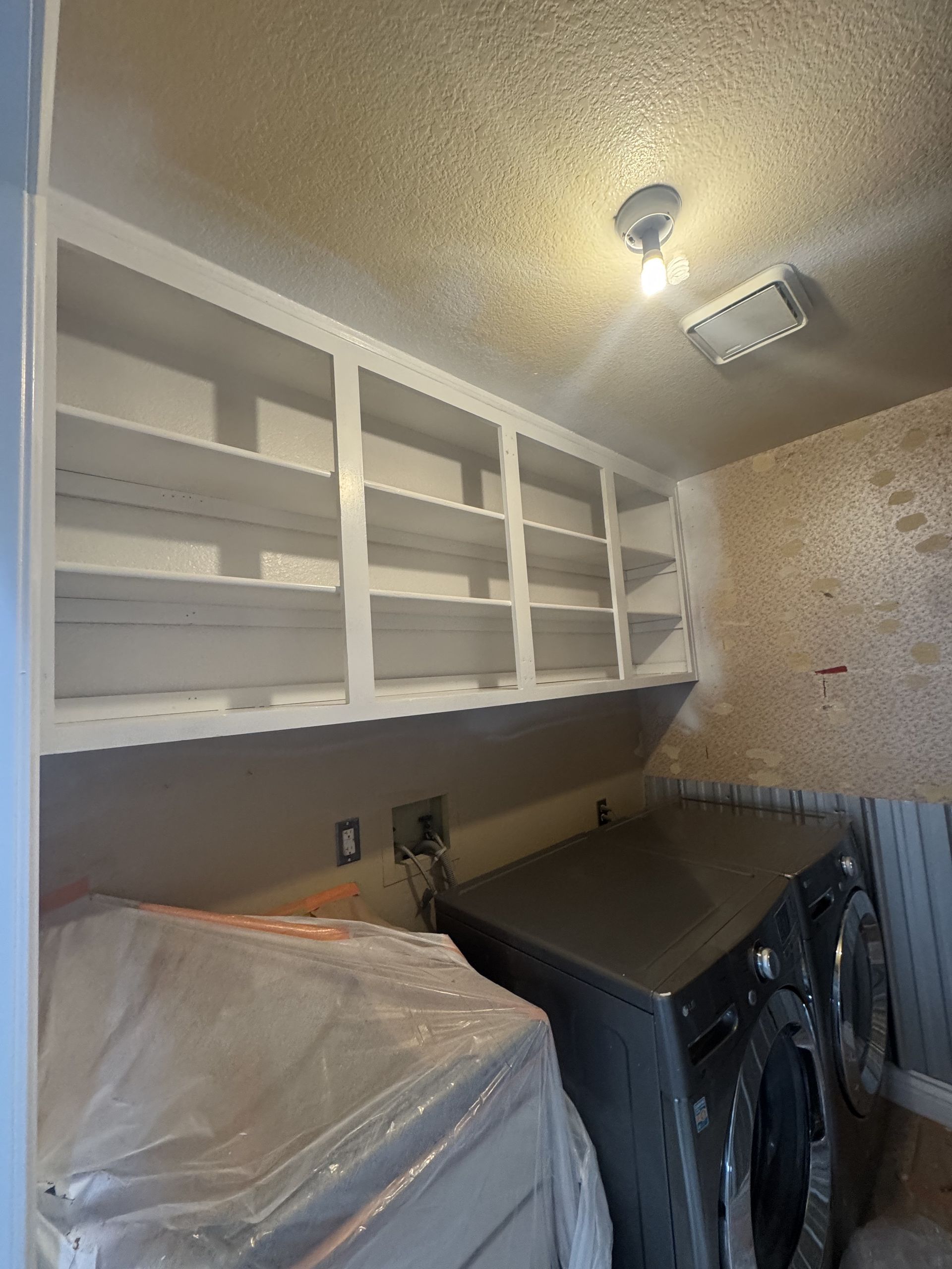 Laundry room with white cabinets, slanted ceiling light, and washer and dryer along the wall