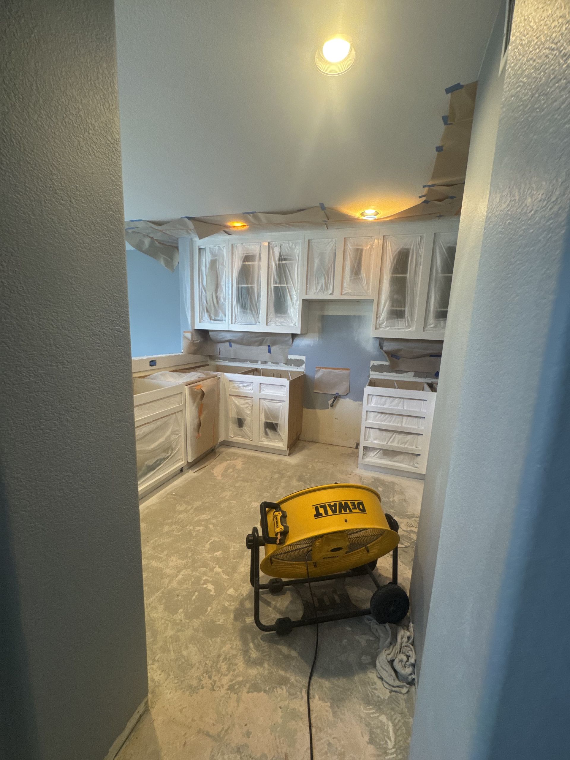 Kitchen under renovation with cabinets installed and a yellow floor fan in the foreground