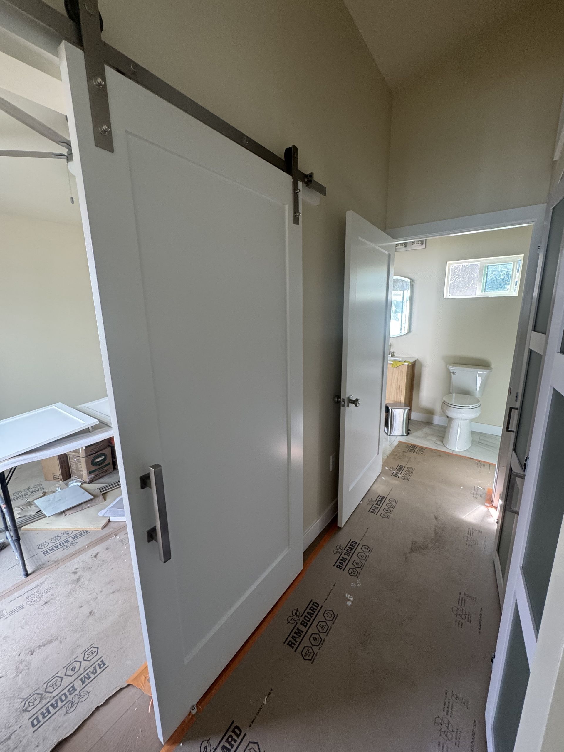 Sliding barn door in a narrow hallway, with a bathroom visible at the end.