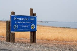 A blue sign that says monument hill launching facility on it.