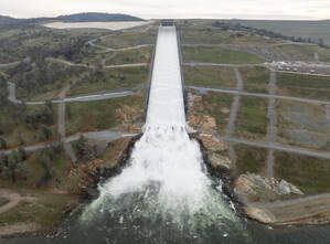 An aerial view of a dam with water coming out of it.