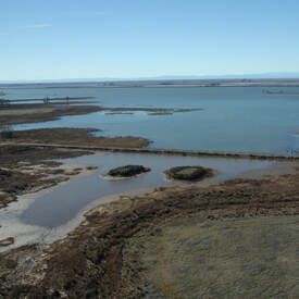 An aerial view of a large body of water surrounded by grass and rocks.