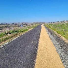A road with a yellow line on the side of it going through a field.