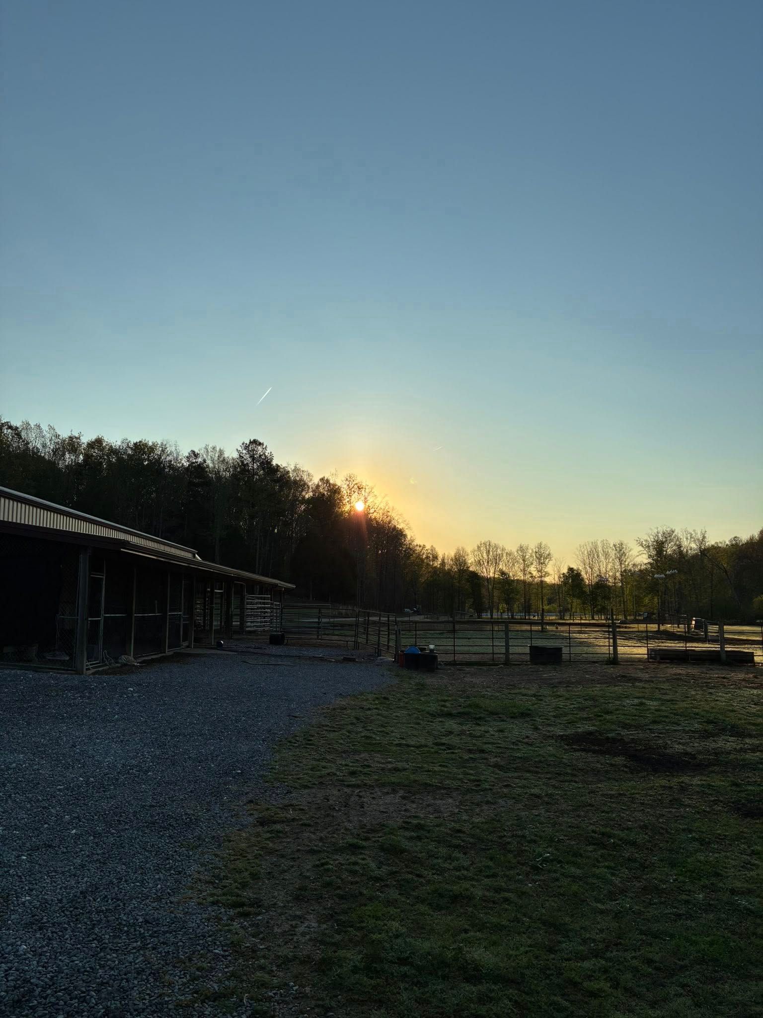 Sunrise over a rural farm field with a barn and trees silhouetted against a clear sky Sunrise over a rural farm field with a barn and trees silhouetted against a clear sky