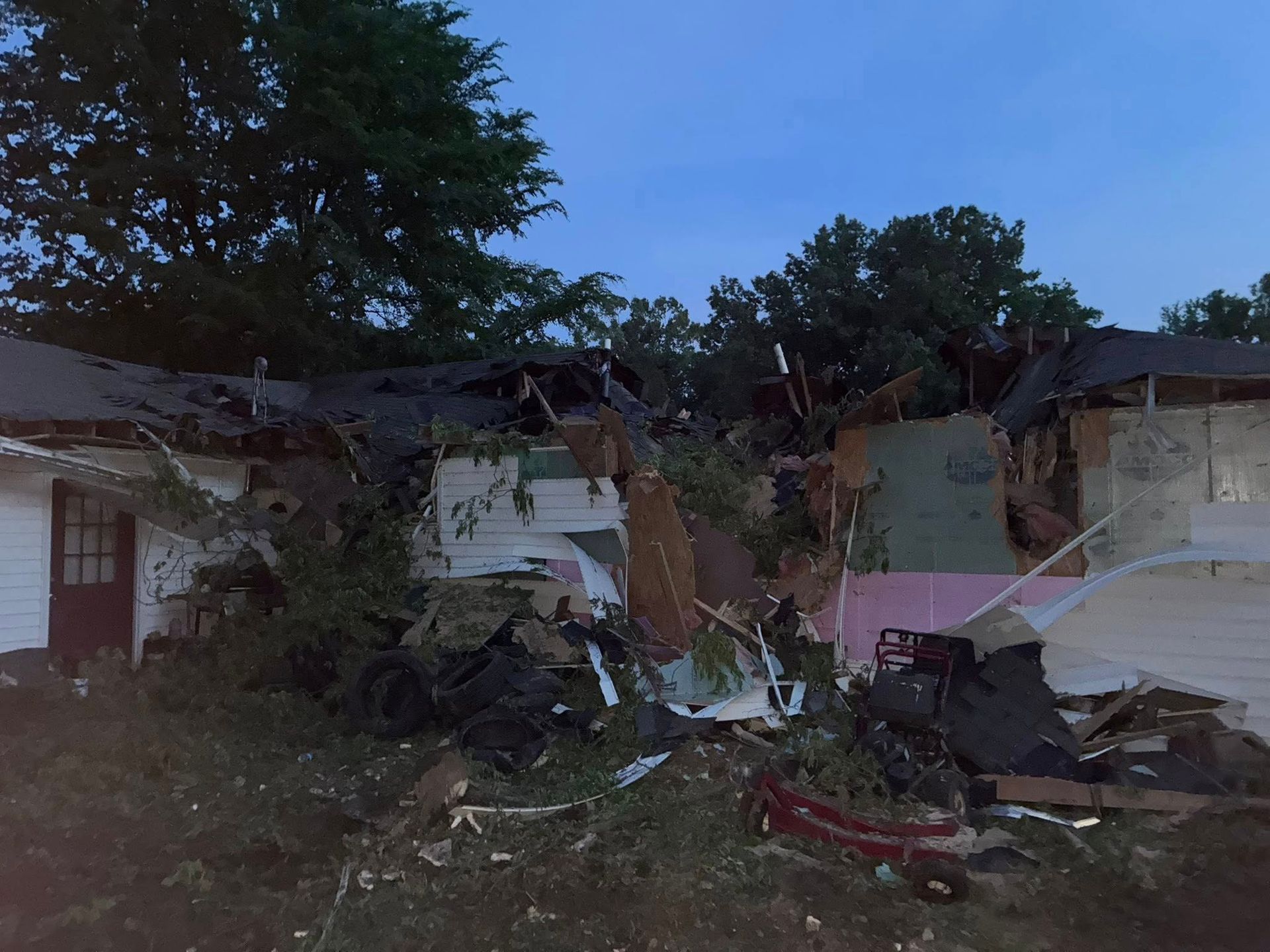 Severe storm damage to a house, with a collapsed roof and scattered debris in the yard. Severe storm damage to a house, with a collapsed roof and scattered debris in the yard.