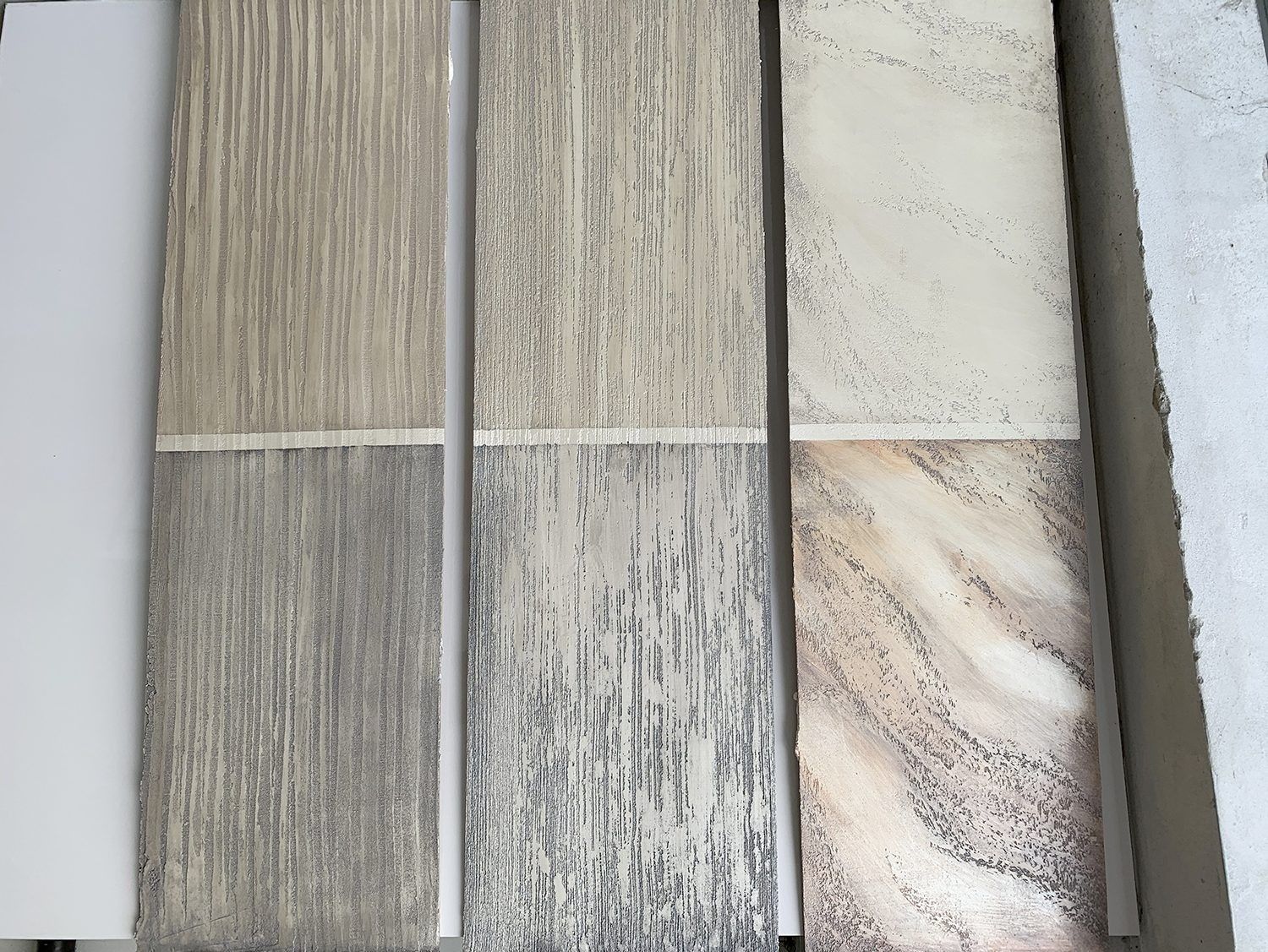 Cinque campioni di piastrelle effetto legno nei toni del grigio, del beige e del bianco, disposti a griglia.