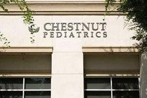 Chestnut Pediatrics sign on a building facade with ivy and windows