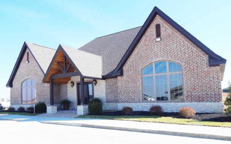 Brick suburban house with a gabled roof, large arched window, and covered front porch.