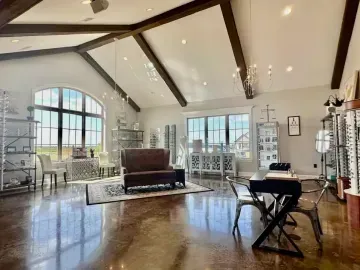 Bright modern living room with vaulted ceiling, large windows, piano, and polished wood floors