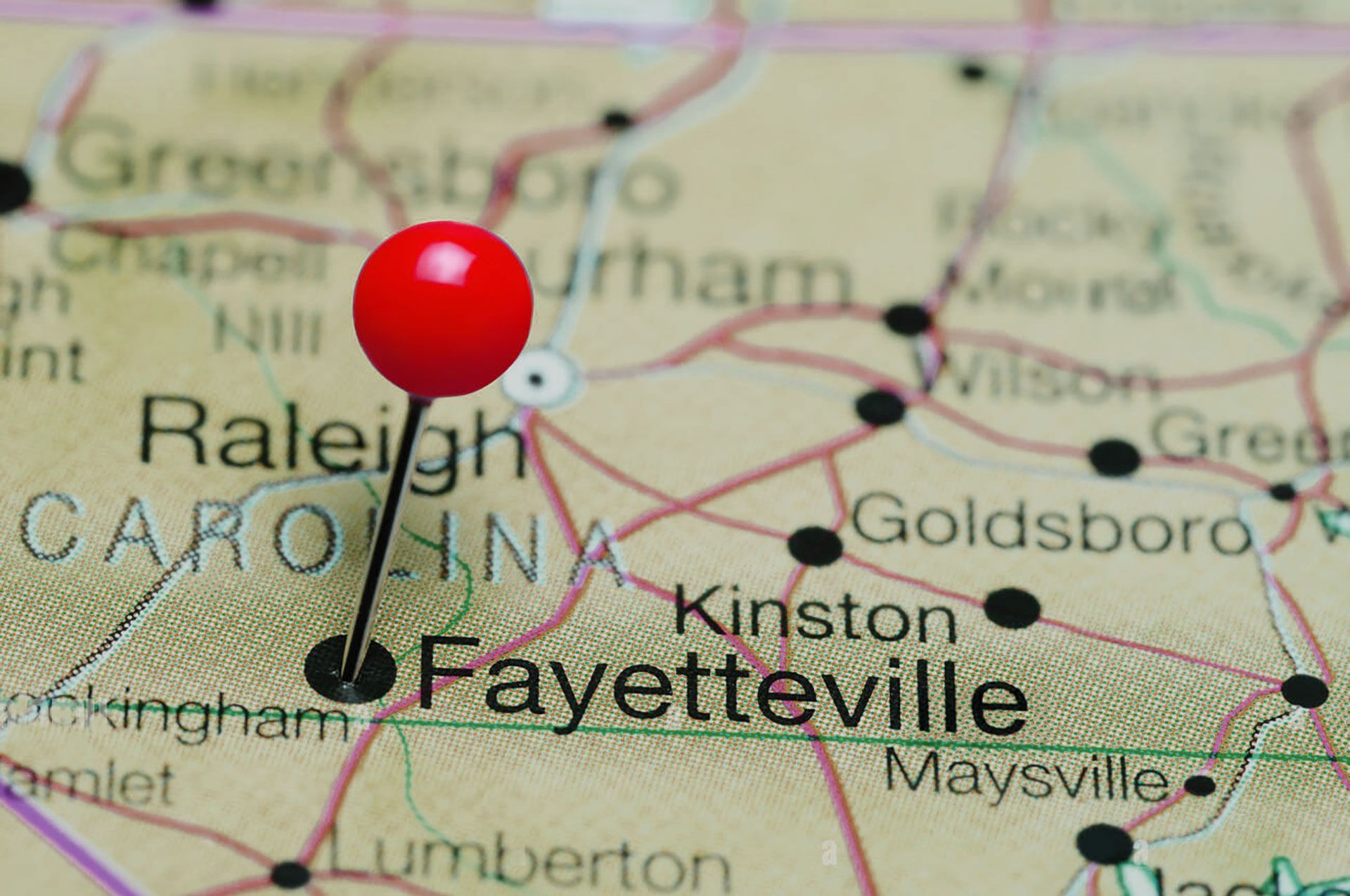A red map pin marks the location of Fayetteville on a map of North Carolina.