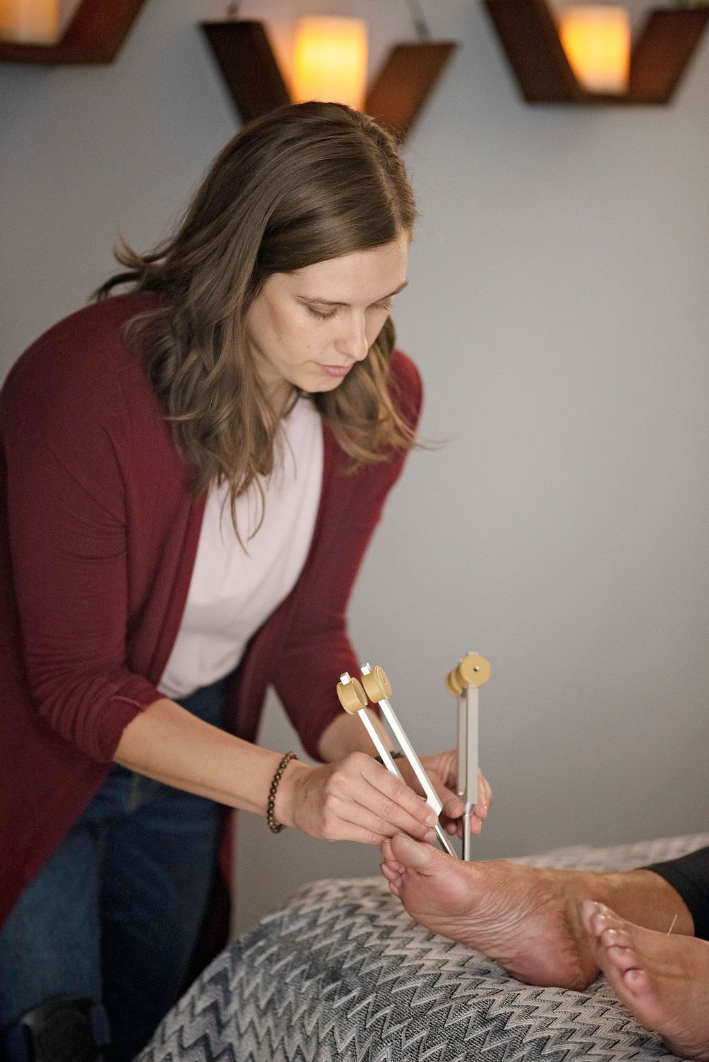 a woman in a red cardigan is working on a person 's foot