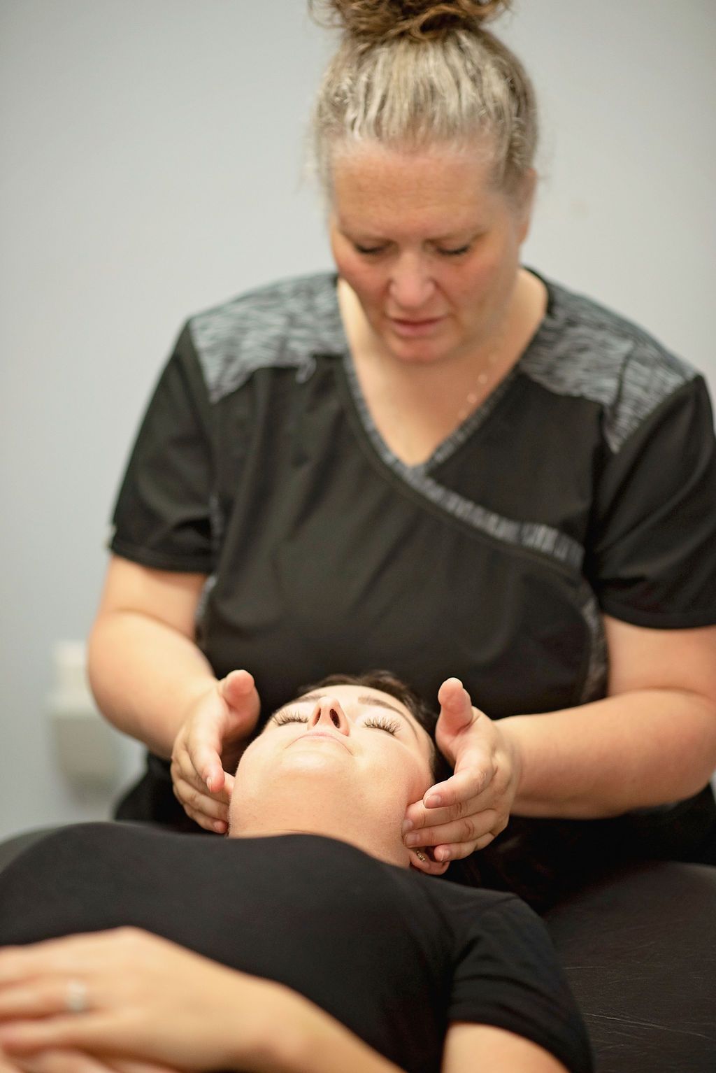 a woman in a black shirt is giving a woman a massage