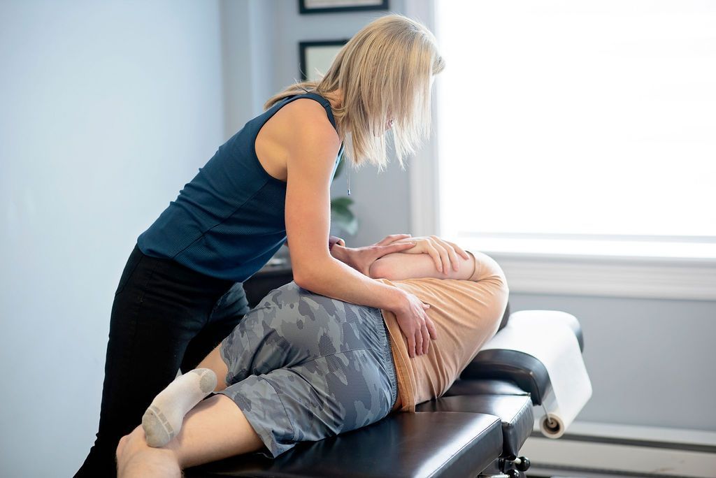 Chiropractor adjusting a patient lying face down on a treatment table in a bright clinic room