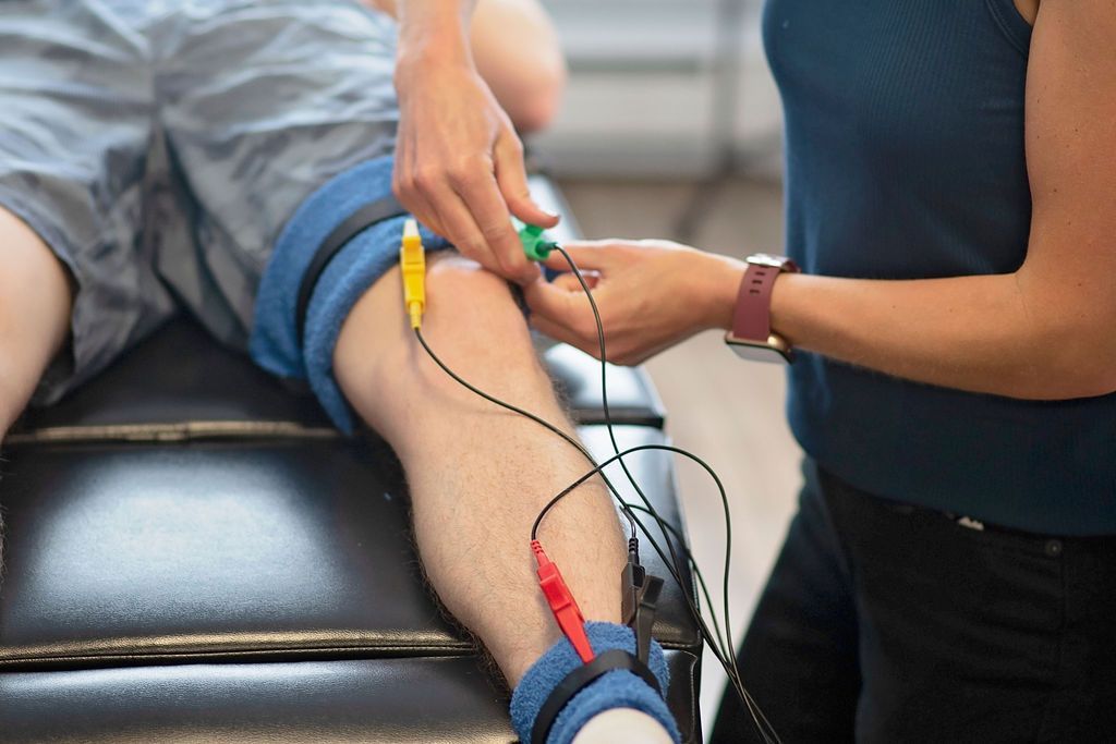 Physical therapist applying electrodes to a patient’s lower leg during treatment