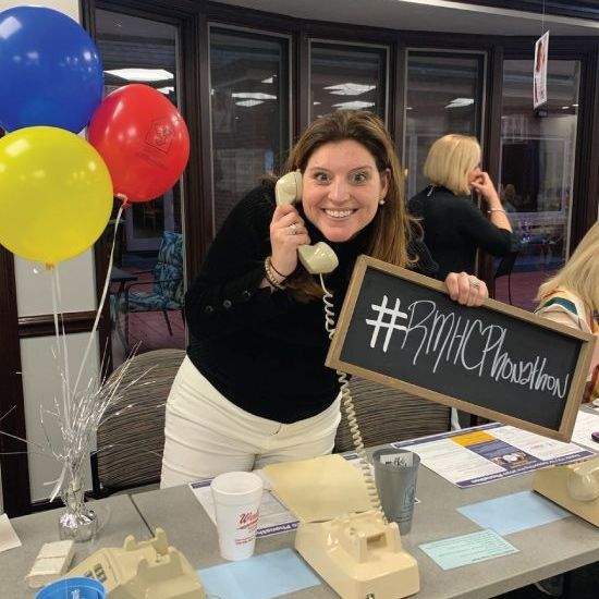A woman talking on a phone while holding a sign that says #rmhcp