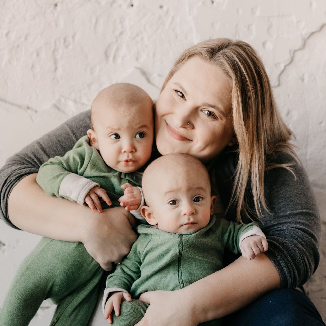 A woman is holding two babies in her arms.