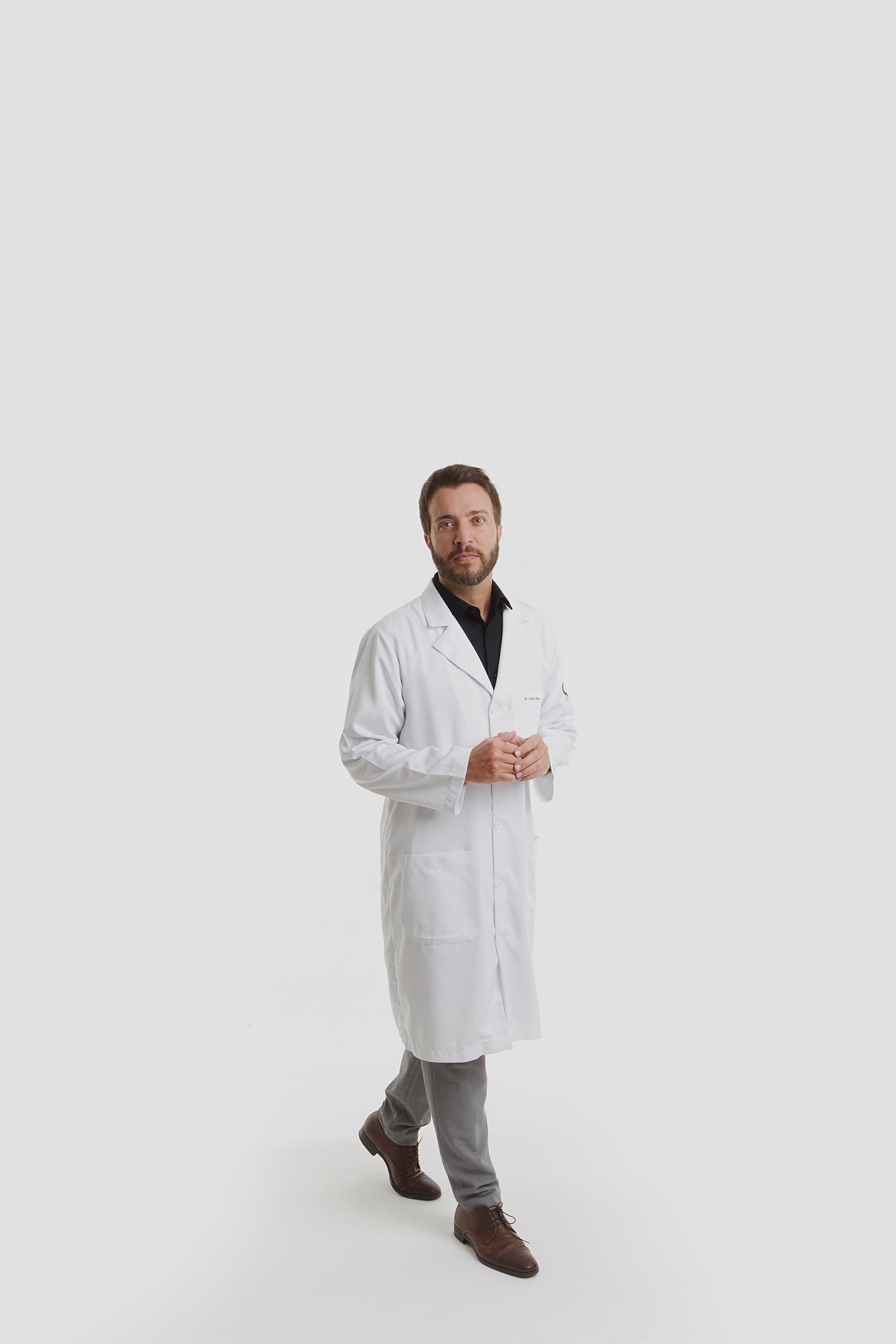 Homem de olhos azuis e barba, de camisa preta, olhando para a câmera com uma expressão séria.