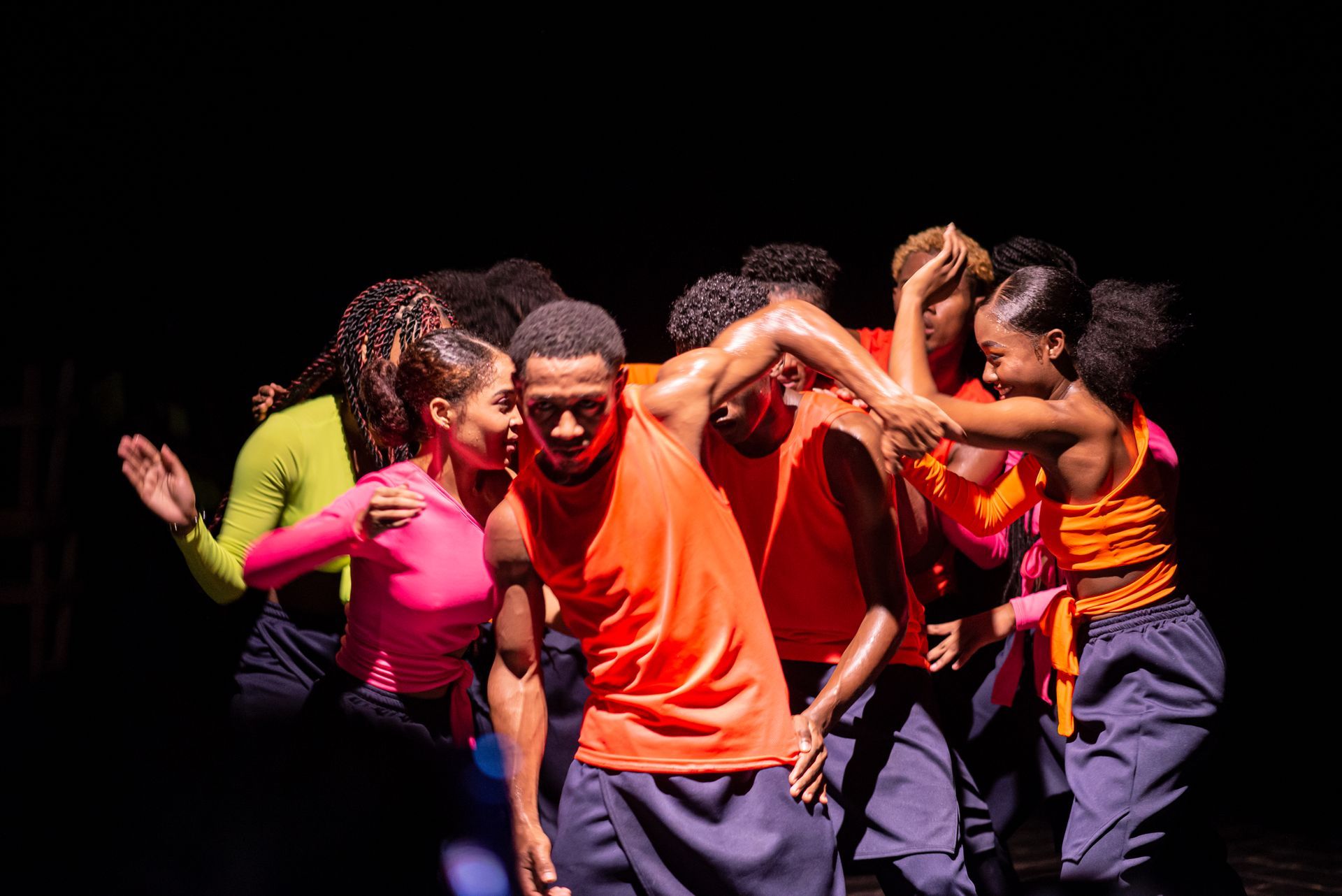 Un grupo de personas está bailando en un escenario en una habitación oscura.