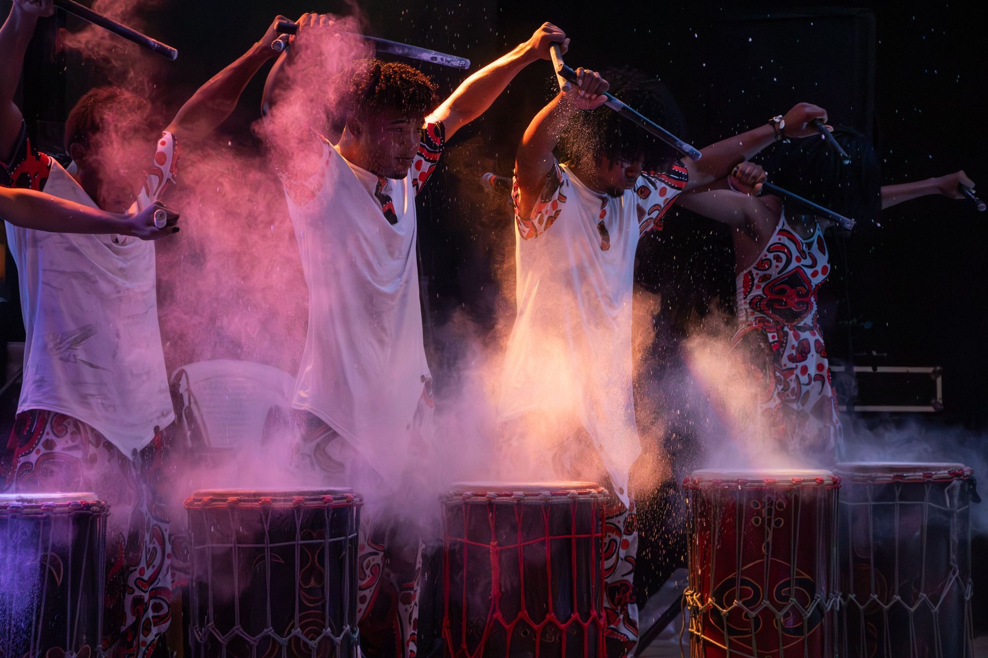 Un grupo de personas está tocando la batería en un escenario y sale humo de ellos. | Memorias danza teatro