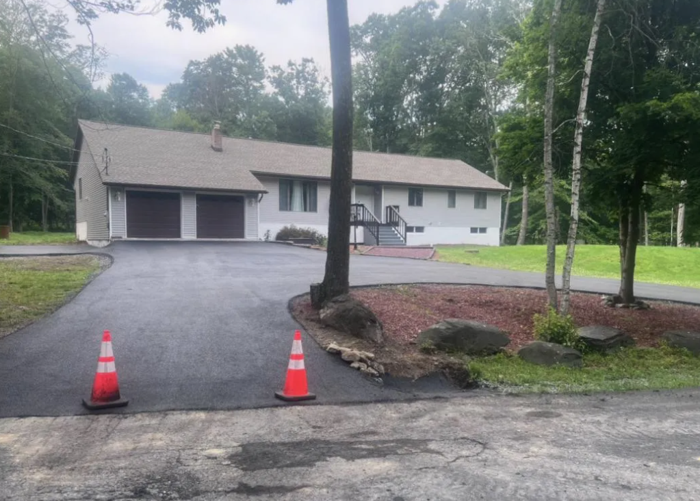 A house with a driveway and two orange cones in front of it