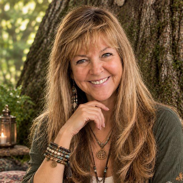 Smiling woman in a green blouse and plaid belt standing among trees, hand on a tree trunk