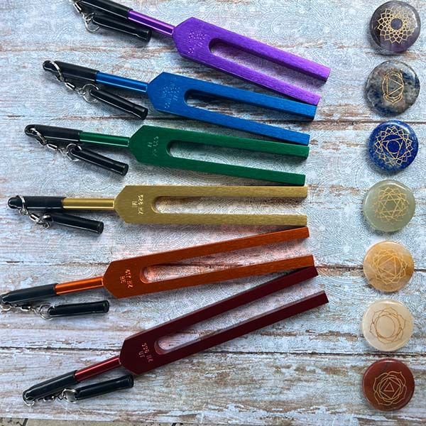 Six colorful energy vitality pens lined up on a wooden surface beside matching decorative round beads