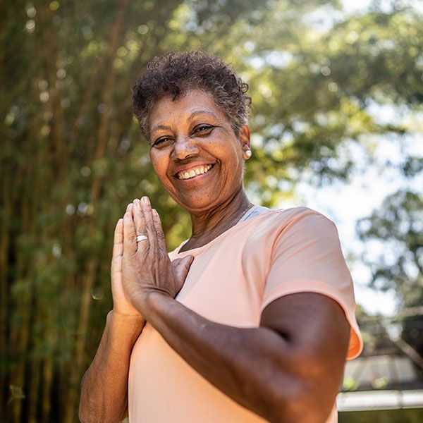 Smiling woman with hands together outdoors in soft sunlight