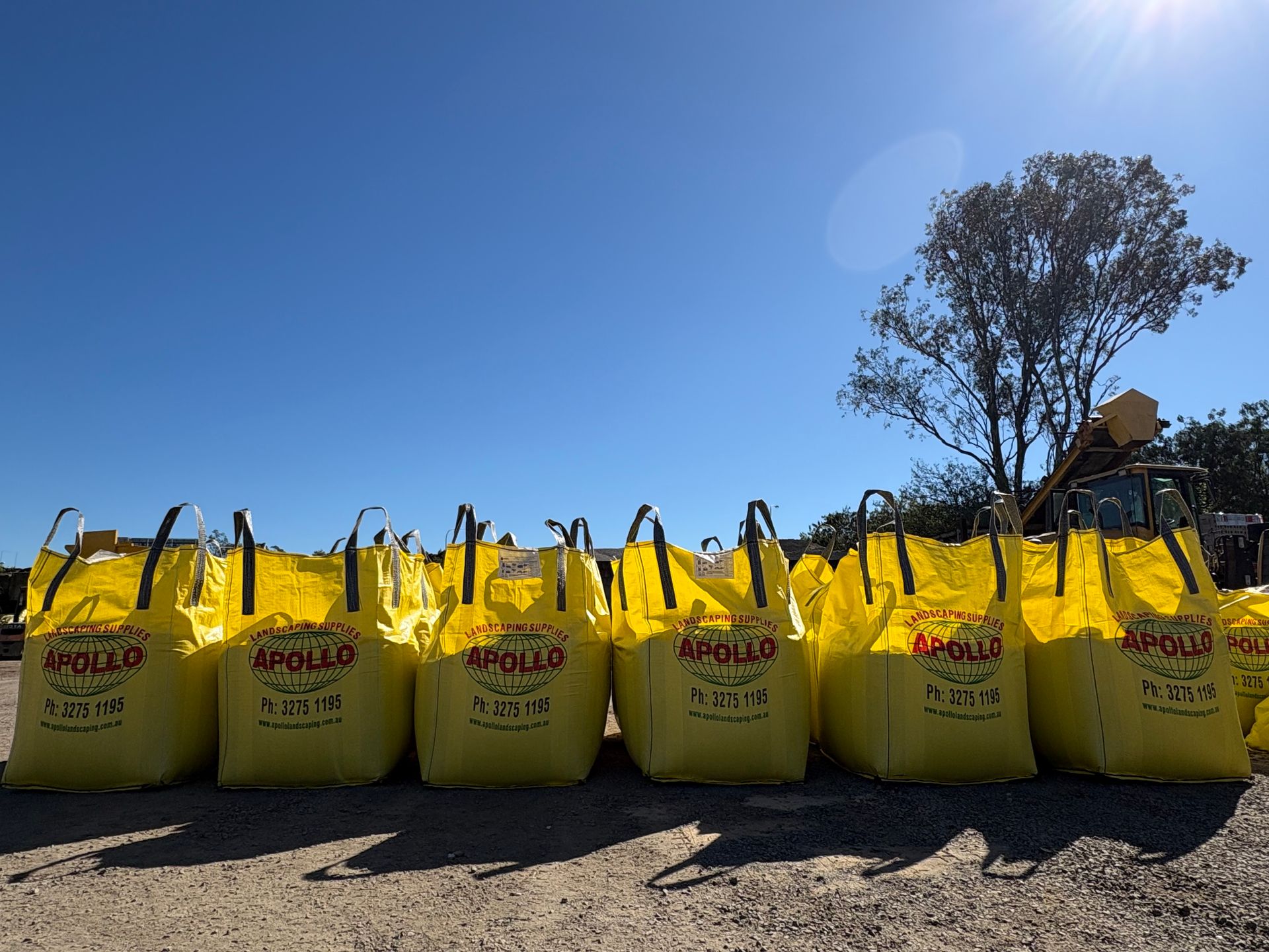 Row of bright yellow Bulka bags lined up outdoors under a clear blue sky