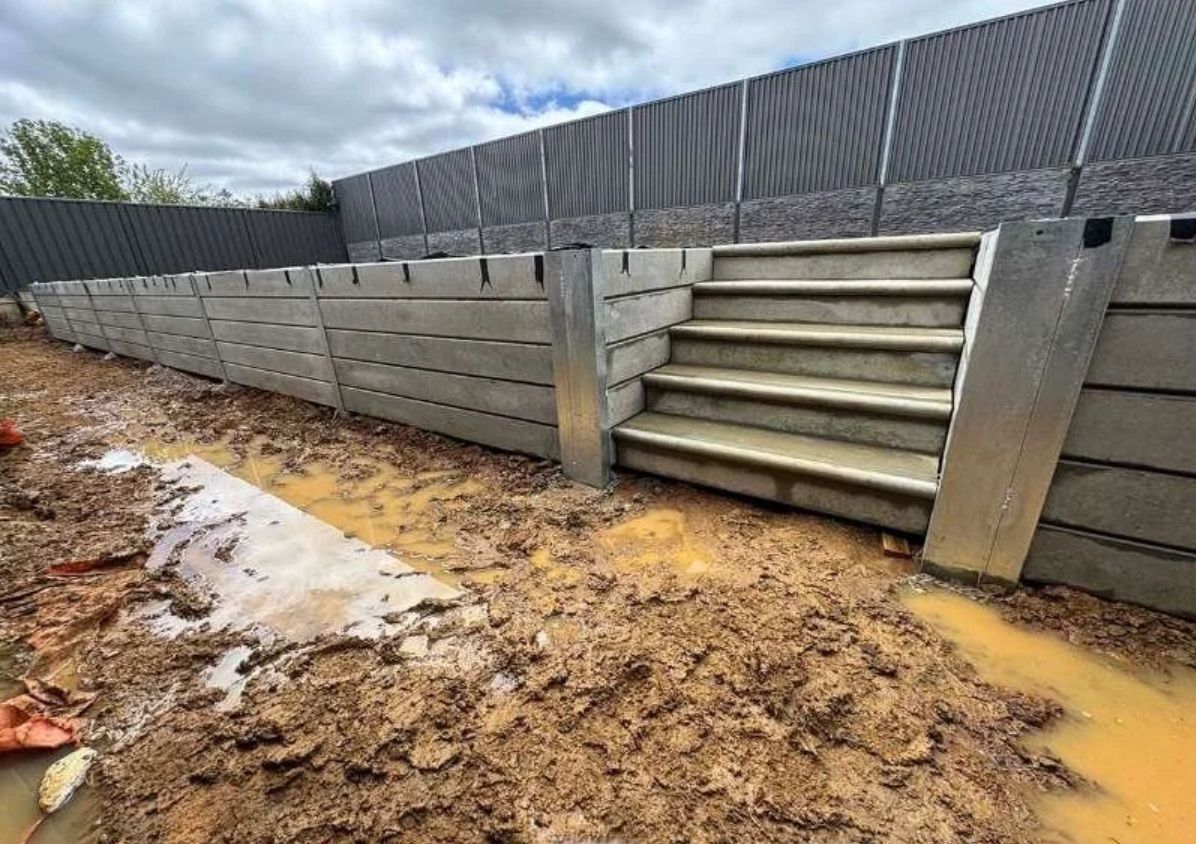 Muddy flooded yard beside concrete retaining wall and steps under overcast sky Muddy flooded yard beside concrete retaining wall and steps under overcast sky