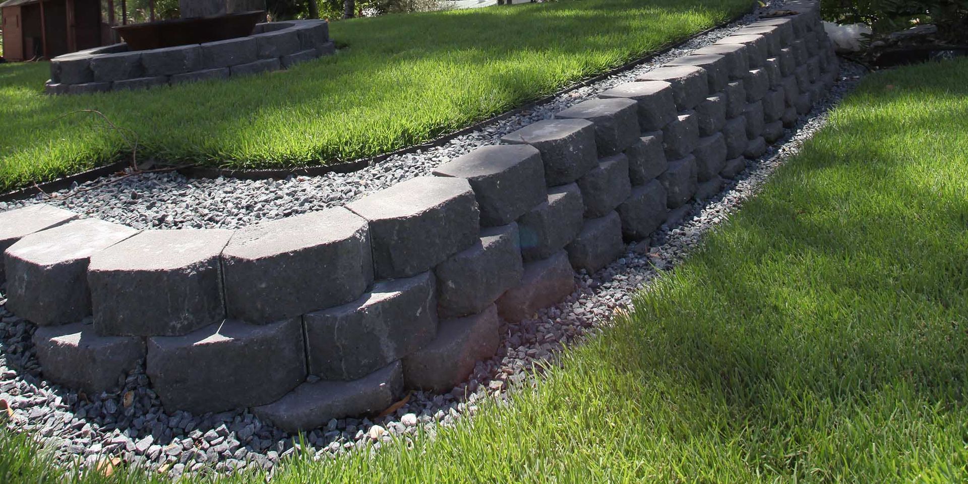 A brick wall in the middle of a lush green lawn