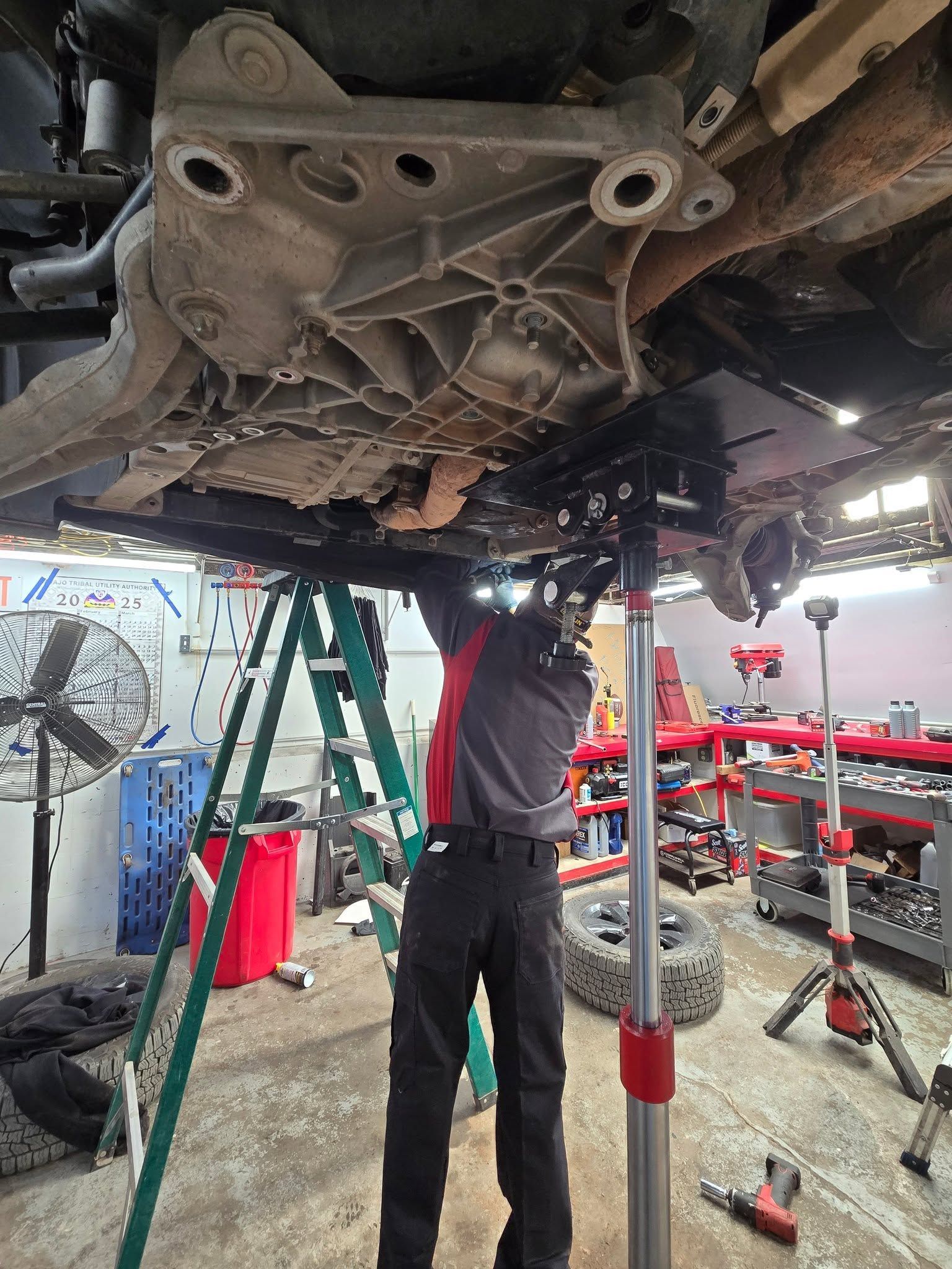 Technician Servicing Undercarriage Of Lifted Vehicle | Burnout Boyz Garage LLC