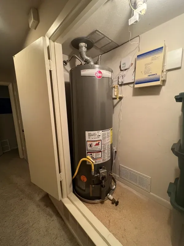 A Rheem water heater in a small utility closet with bi-fold doors.