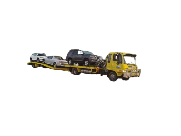 A yellow tow truck is carrying three cars on a trailer.