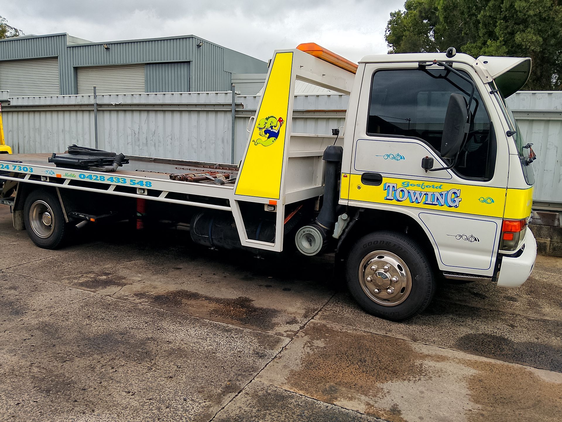 A yellow and white tow truck is parked in a parking lot.