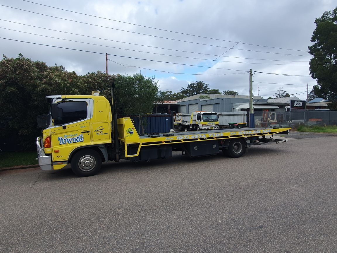 A yellow tow truck is parked on the side of the road.