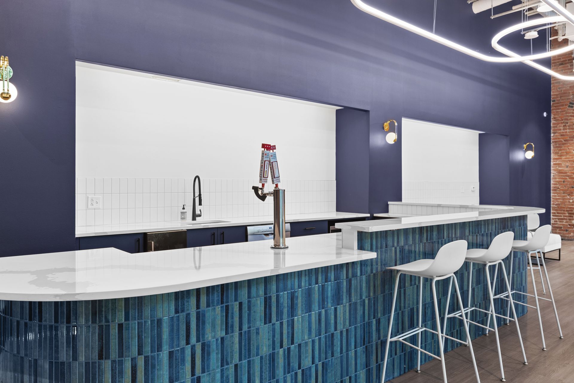 Modern blue-and-white bar interior with stools, curved counter, and a person behind the counter