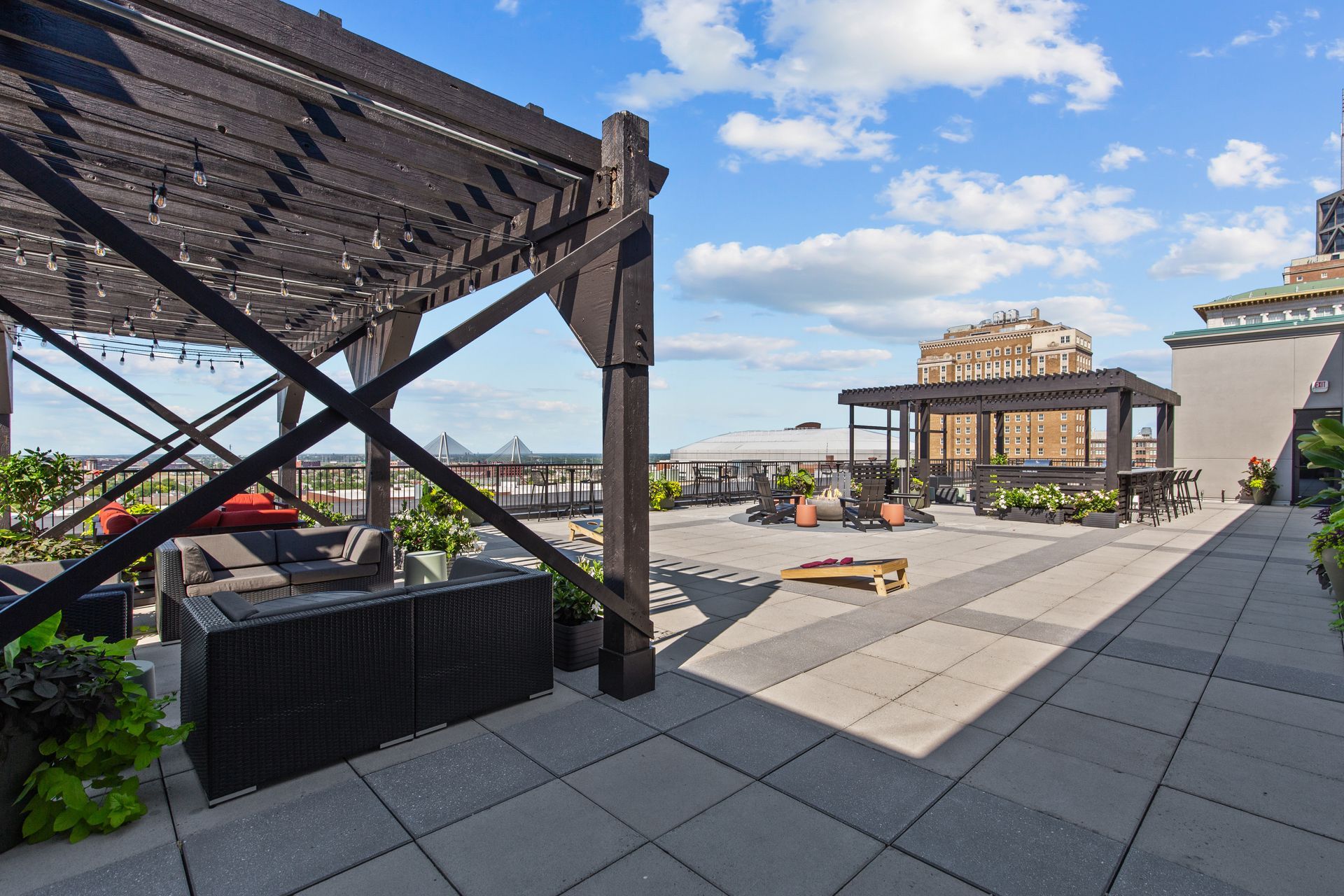 Rooftop terrace with pergola, seating, and city skyline under a blue sky